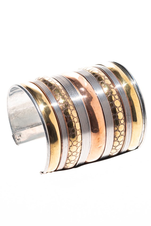 Gold and silver bangles on a person's wrist against a white fabric background